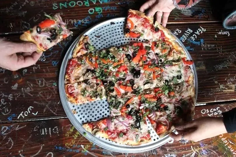 Overhead view of deep-dish pizzas with toppings and graffitied wooden table