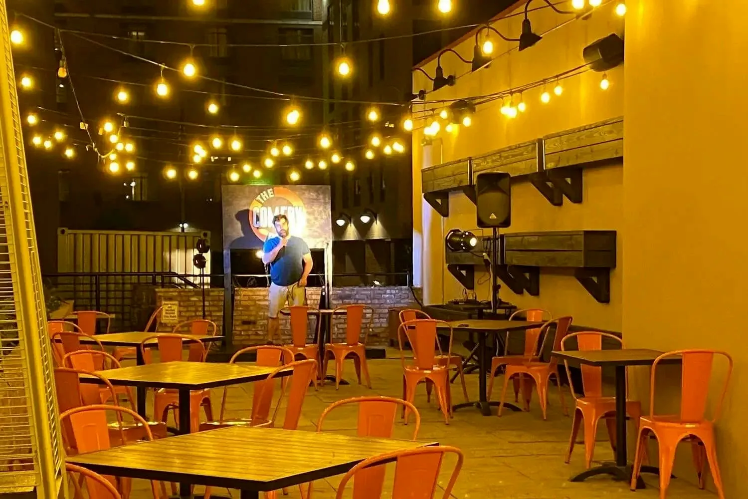 Outdoor patio dining with string lights and orange chairs at Gino’s East