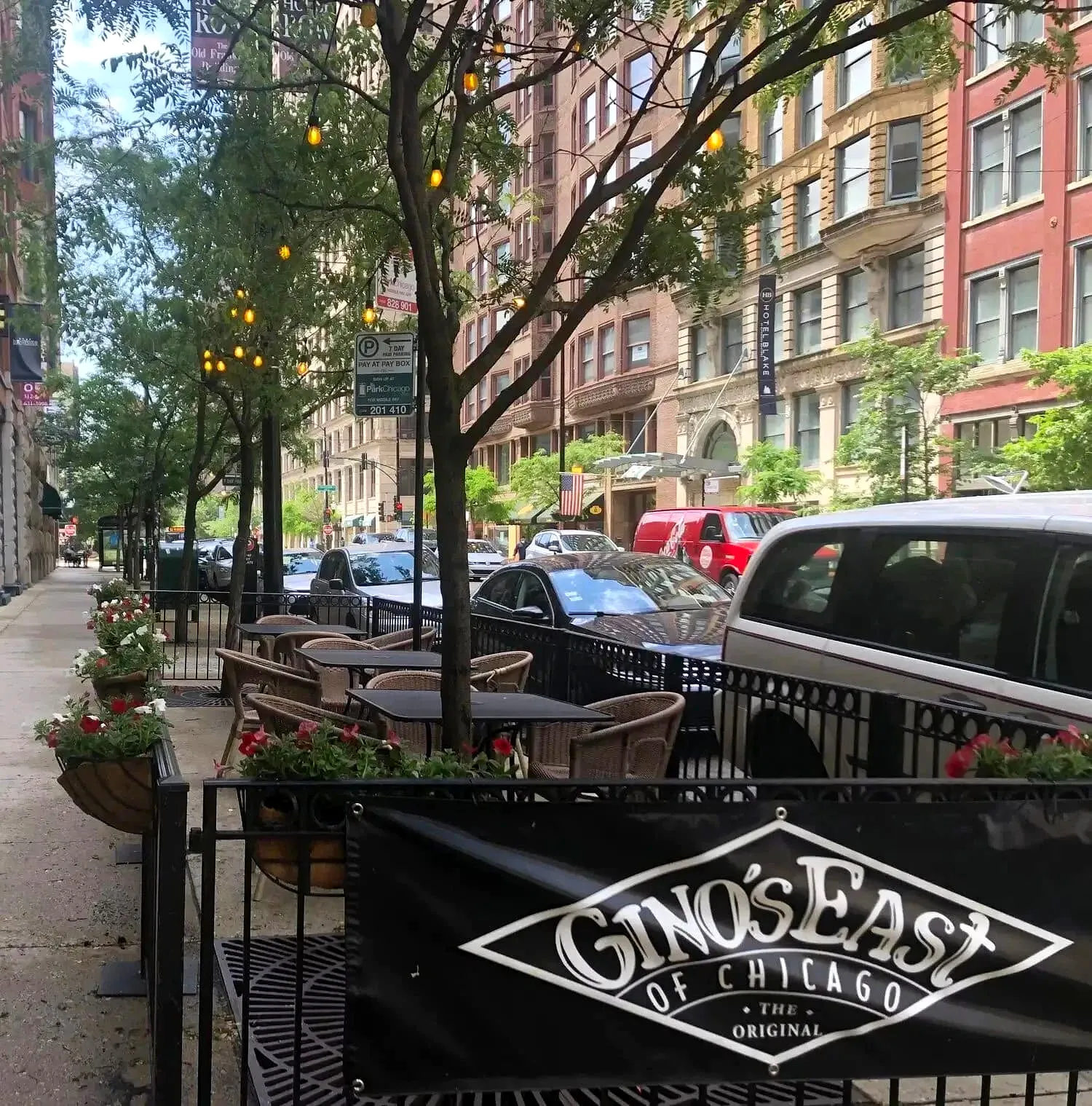 Gino’s East outdoor seating area with tables, trees, and city street in Chicago