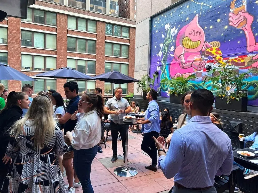 Guests mingling on a rooftop patio event space decorated with a colorful mural
